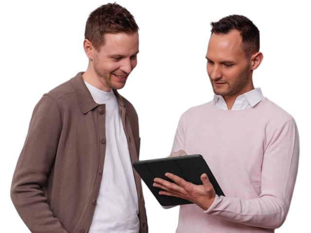 Michael Fürgut und Sebastian Fischer, Steuerberater für digitale Unternehmen aus München, schauen gemeinsam auf ein Tablet