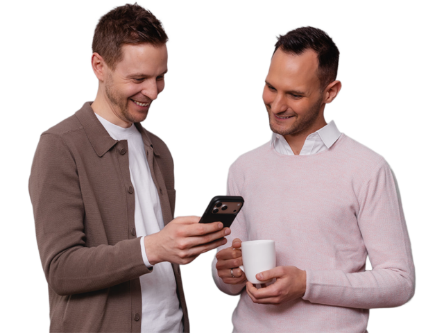 Michael Fürgut und Sebastian Fischer, Steuerberater für E-Commerce aus München, schauen gemeinsam auf ein Smartphone,